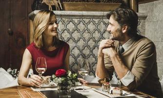 A romantic candlelit dinner for two at a table. The atmosphere is cozy and elegant, complemented by flowers and decorative elements.