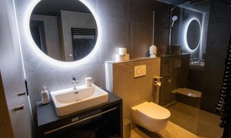 A modern bathroom with an elegant sink and a wall-mounted toilet. The round mirrors and the simple colors create a stylish atmosphere.