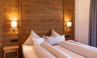 A cozy bedroom with wooden decor and two single beds. The soft lighting creates an inviting atmosphere.