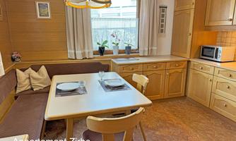 A cozy kitchen with wooden furniture and a dining area. The room has a window overlooking the surroundings and is bright and inviting.