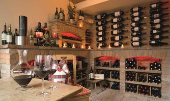 A stylish wine cellar with shelves full of wine bottles. Two glasses of red wine and a decanter are on a rustic table.