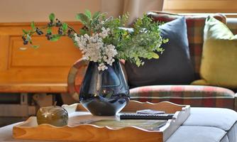 A beautiful table with a vase full of fresh flowers and a large, soft couch in the background. The colors create a cozy atmosphere.