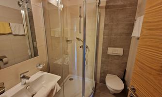 A modern bathroom with a separate shower and elegant sink. The walls are bright and the amenities are contemporary.