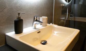 A modern sink with an elegant faucet and soap dispenser. In the background, a stylish wall can be seen.
