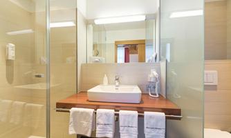 A modern bathroom with an elegant sink installation and large mirrors. Towels are neatly hanging near the sink.