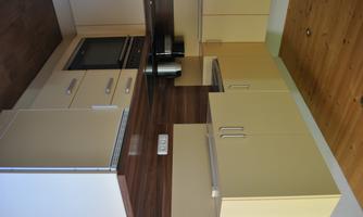 A modern kitchen with light cabinets and a wooden surface. It is well equipped with a stove and a kettle.