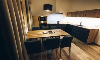 A modern kitchen with a wooden tray and black chairs. The room is well-lit and has a cozy atmosphere.