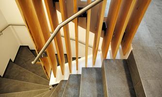 A modern staircase with curved steps and a metal railing. The walls are designed with wooden paneling.