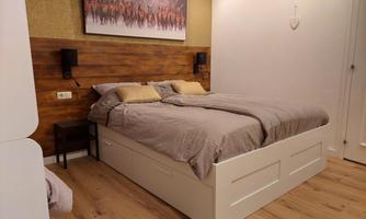A cozy bedroom with a large, bright bed and wooden walls. A beautiful picture on the wall complements the decor.