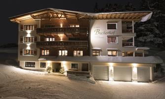 A charming building in alpine style gently glows under the night sky. Surrounded by snow-covered landscapes, it radiates coziness and warmth.