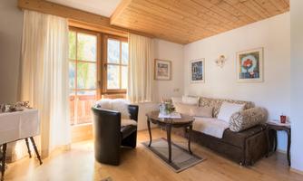 A cozy living room with a sofa and a table.  
Large windows let in plenty of light and offer a view of the outdoor area.