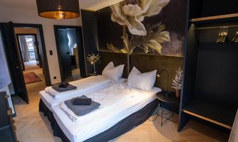 A modern bedroom with two single beds and an elegant wall design. There is a cozy atmosphere with stylish furniture and decorative elements.