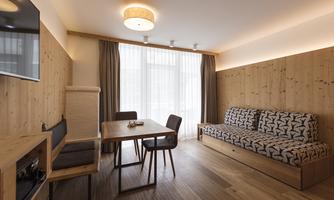 A modern living room with wooden walls and large windows. There is a sofa, a table, and a television.