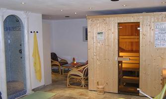A relaxing wellness area with a sauna and a shower area. There are cozy chairs and soft lighting for a pleasant atmosphere.