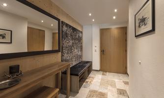 A modern entrance area with wood and stone accents. A large mirror and a seating area create an inviting atmosphere.