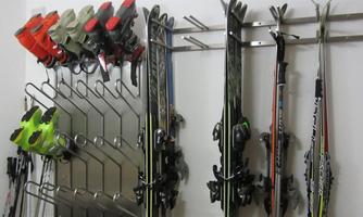A ski equipment set with skis and ski boots is neatly hanging on the wall. The colors are mainly black, gray, and bright green.