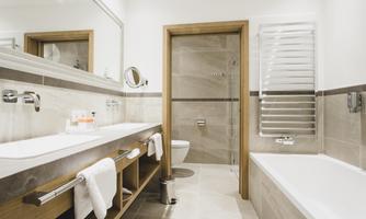 A modern bathroom with a bathtub and a shower. The walls are painted in neutral colors, and there is a large mirror above the sink.