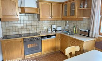 A cozy kitchen with wooden cabinets and a modern stove. The room is bright and inviting, ideal for preparing meals.