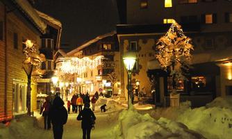 A picturesque winter street, illuminated with festive lights. People stroll through the snow and enjoy the winter atmosphere.