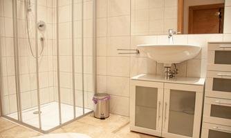 A modern bathroom with a glass shower and a sink. The room is bright and clean, with a neutral color tone.