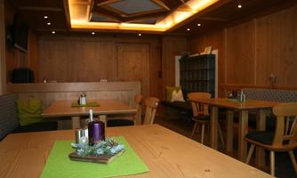 A cozy restaurant with wooden walls and tables. Decorative candles and green tablecloths are on the tables.