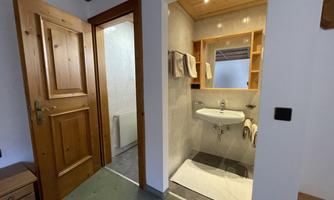 A simple bathroom with a sink and a mirror. The walls are light and there are wooden panels.