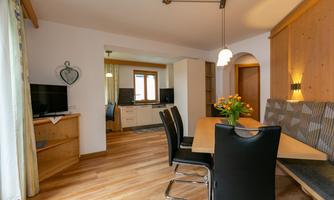 A stylish dining room with a wooden table and black chairs. The decor is bright and friendly, featuring a beautiful flower arrangement on the table.