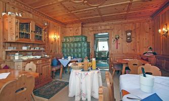 A cozy, rustic restaurant with wooden walls and traditional furniture. The table is set, and there are various drinks on the tablecloth.
