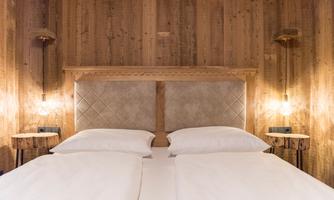 A cozy bedroom with a double bed and warm wooden details. The soft lighting creates a relaxed atmosphere.