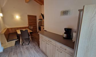 A modern kitchen with wooden furniture and a dining table. The surroundings are bright and inviting.