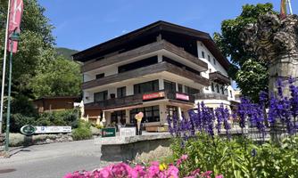 A charming building in a picturesque setting with colorful flower beds in the foreground. The sky is clear and sunny, perfect for relaxed days.