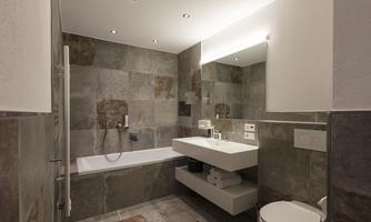 A modern bathroom with elegant tiles and clean lines. It features a bathtub, a sink, and a toilet.