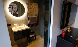 A modern bathroom with an elegant vanity unit and a large mirror. The walls are painted in neutral tones, and there are stylish towels and decorative elements.