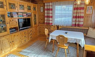 A cozy living room with wood paneling and a dining table.