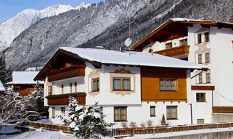 A mountain house in winter, covered with snow. The mountains in the background are majestic and invite relaxation.