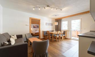 A modern living room with a cozy seating area and a dining space. Large windows provide plenty of daylight and an inviting atmosphere.