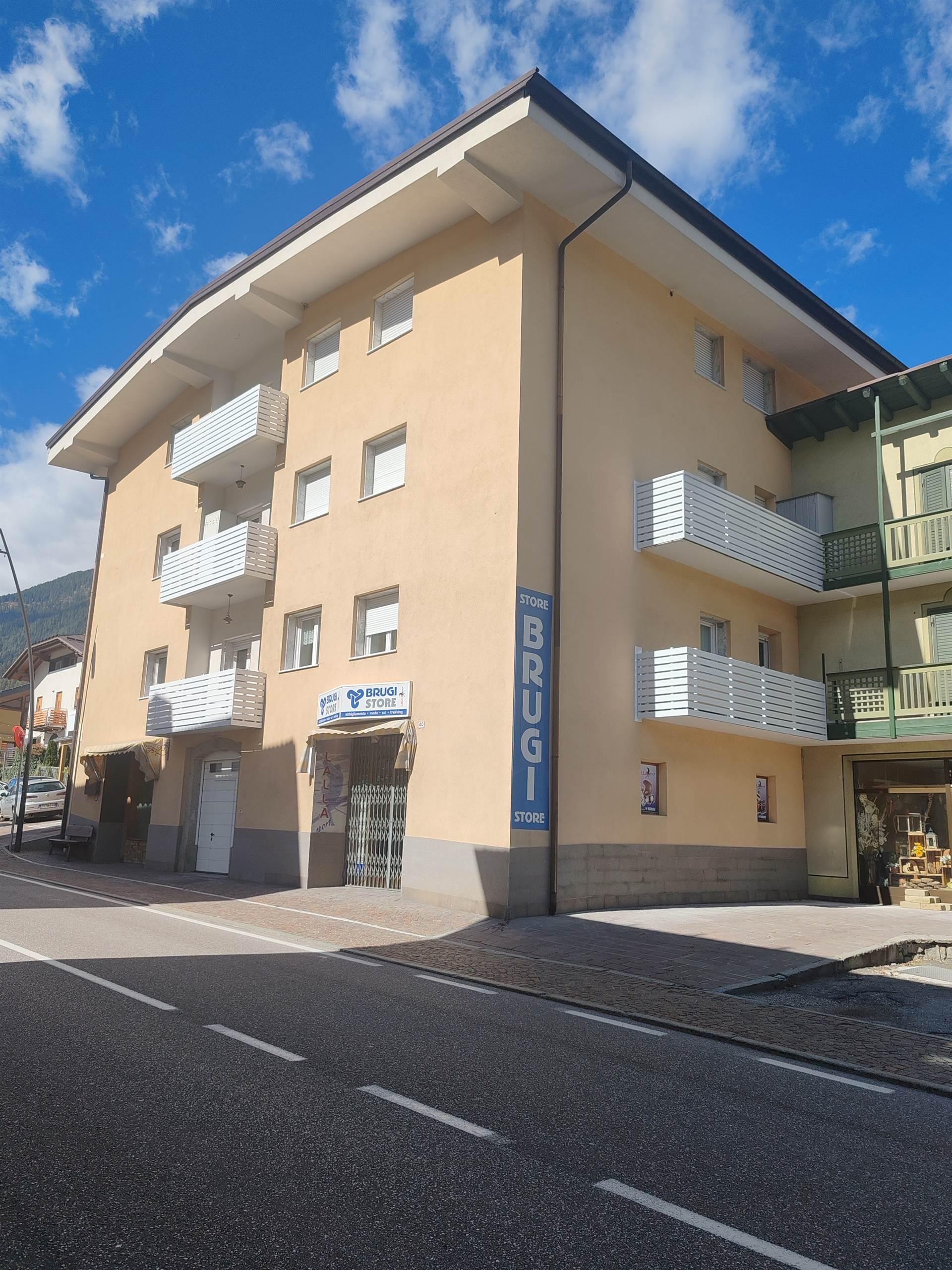 A modern residential building with white balconies. It is located along a street in an urban area.