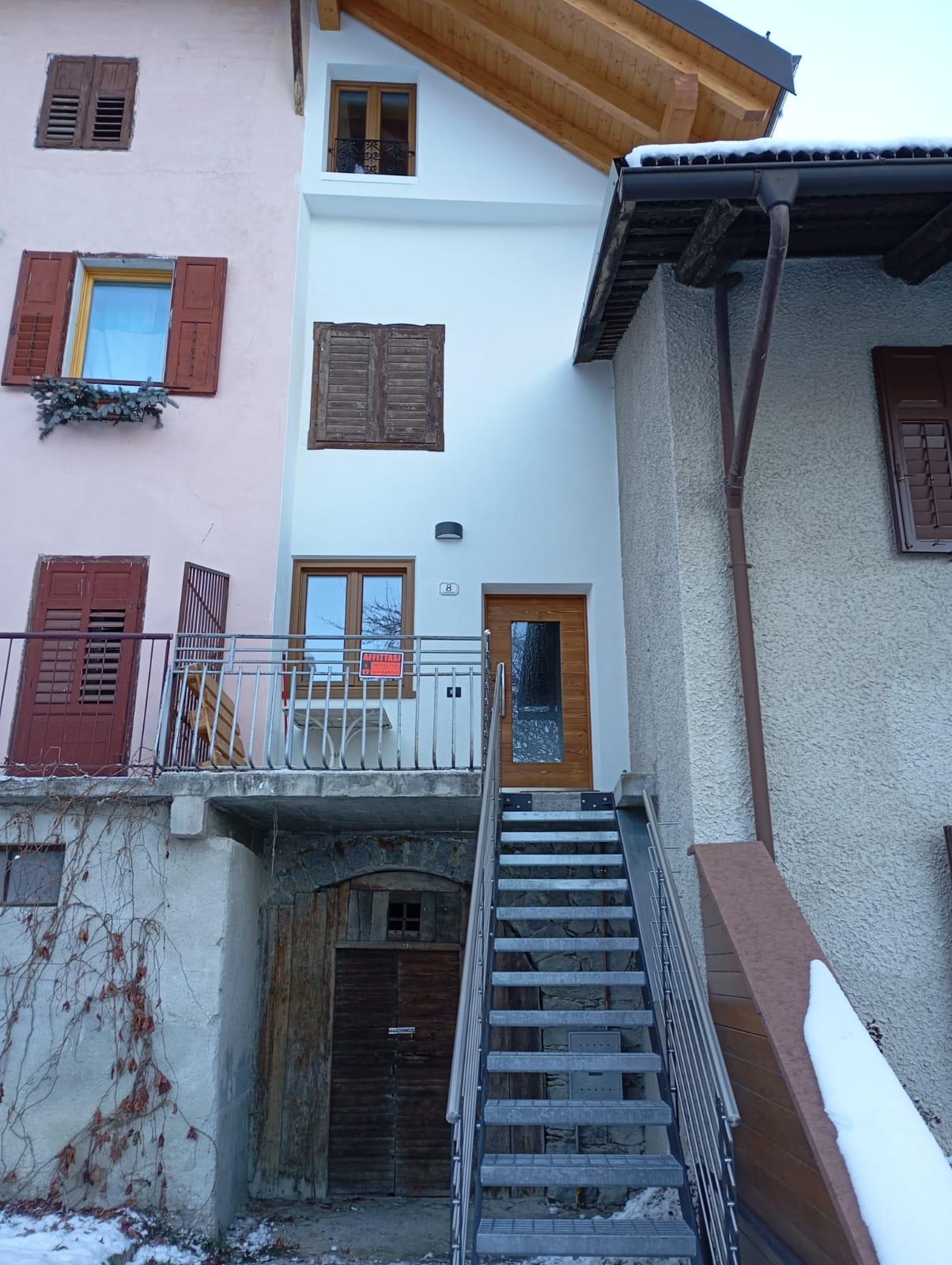 A house with an external staircase and a balcony. The ceiling is wooden and the surrounding area is covered in snow.