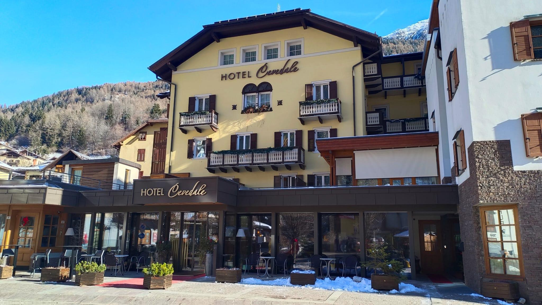 Un accogliente hotel di montagna con un design tradizionale e splendide finestre. Si vede un paesaggio innevato e montagne sullo sfondo.