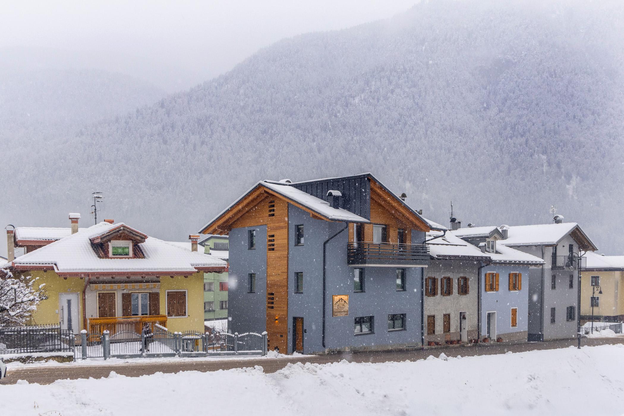 Eine Winterlandschaft mit schneebedeckten Häusern. Die Berge im Hintergrund schaffen eine ruhige und eindrucksvolle Atmosphäre.