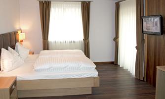 A modern bedroom with a double bed and light curtains. The decor is simple and cozy, ideal for relaxation.