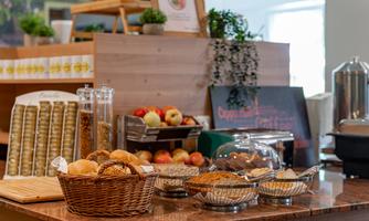 A lavish breakfast buffet featuring fresh rolls, apples, and a variety of pastries. The rustic counter is inviting and well-stocked.