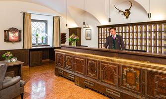 An elegant reception area with a stylish wooden reception desk. In the background, there are plants and a cozy seating area.