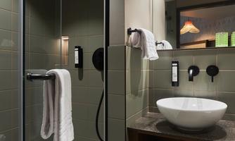 A modern bathroom with a shower and a sink. The walls are in a stylish gray tone, and there are towels nearby.