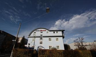 A blue building named "Haus Gretsch" with white windows. The sky is clear with some clouds.