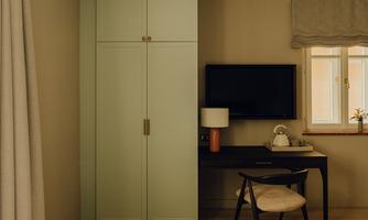 A modern room with a simple design. There is a desk, a television, and a wardrobe in soft colors.
