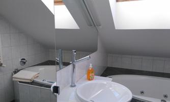 A modern bathroom with a large bathtub and a sink. The room has skylights that provide plenty of natural light.