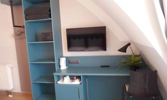 A modern room with a blue desk, a TV on the wall, and a bookshelf. The room is bright and decorated in a minimalist style.