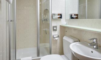 A modern bathroom with a shower, sink, and toilet. The walls are tiled in light colors, and the space feels clean and inviting.