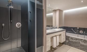 A modern bathroom with a glass shower and a bathtub. The walls are in neutral colors, and there is bright lighting.